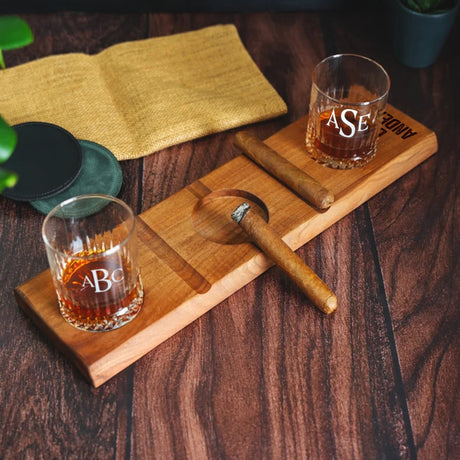 a wooden cutting board topped with two glasses of whiskey