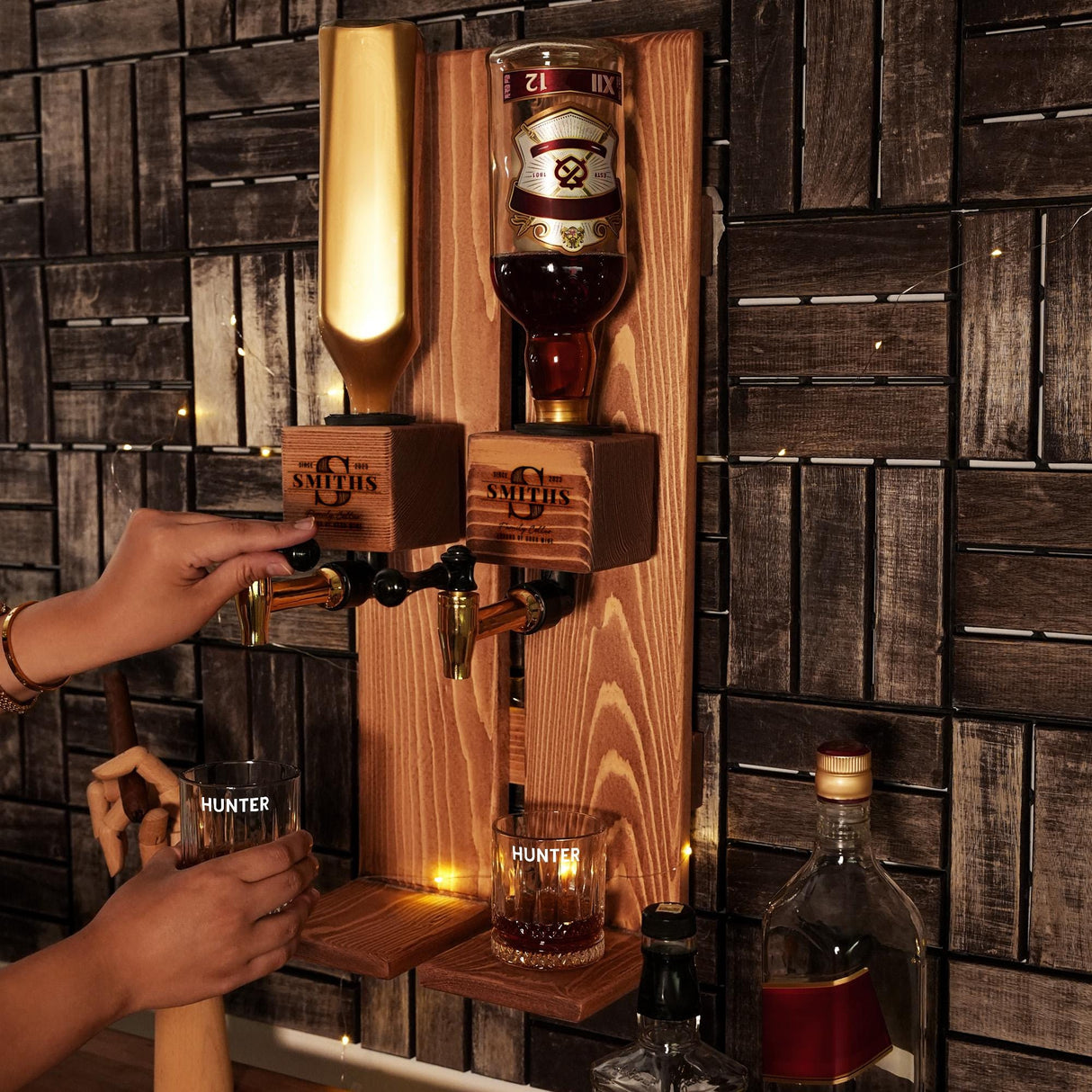 a person holding a glass in front of a wall mounted liquor dispenser