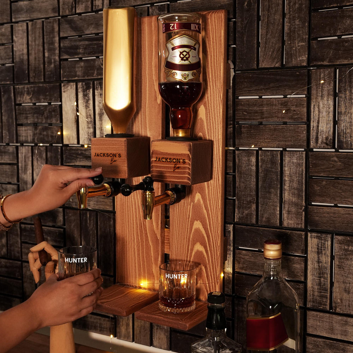 a person holding a glass in front of a wall mounted liquor dispenser