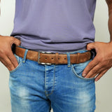 a man wearing a belt with his hands in his pockets