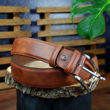 a brown leather belt sitting on top of a tree stump