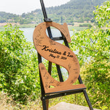 a wooden sign with writing on it sitting in front of a lake