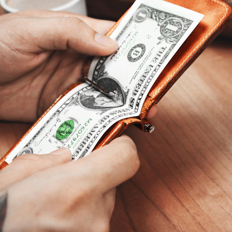 a person holding a wallet with one dollar bill sticking out of it