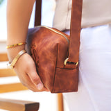 a woman is holding a brown purse in her hand