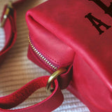 a close up of a red purse on a bed