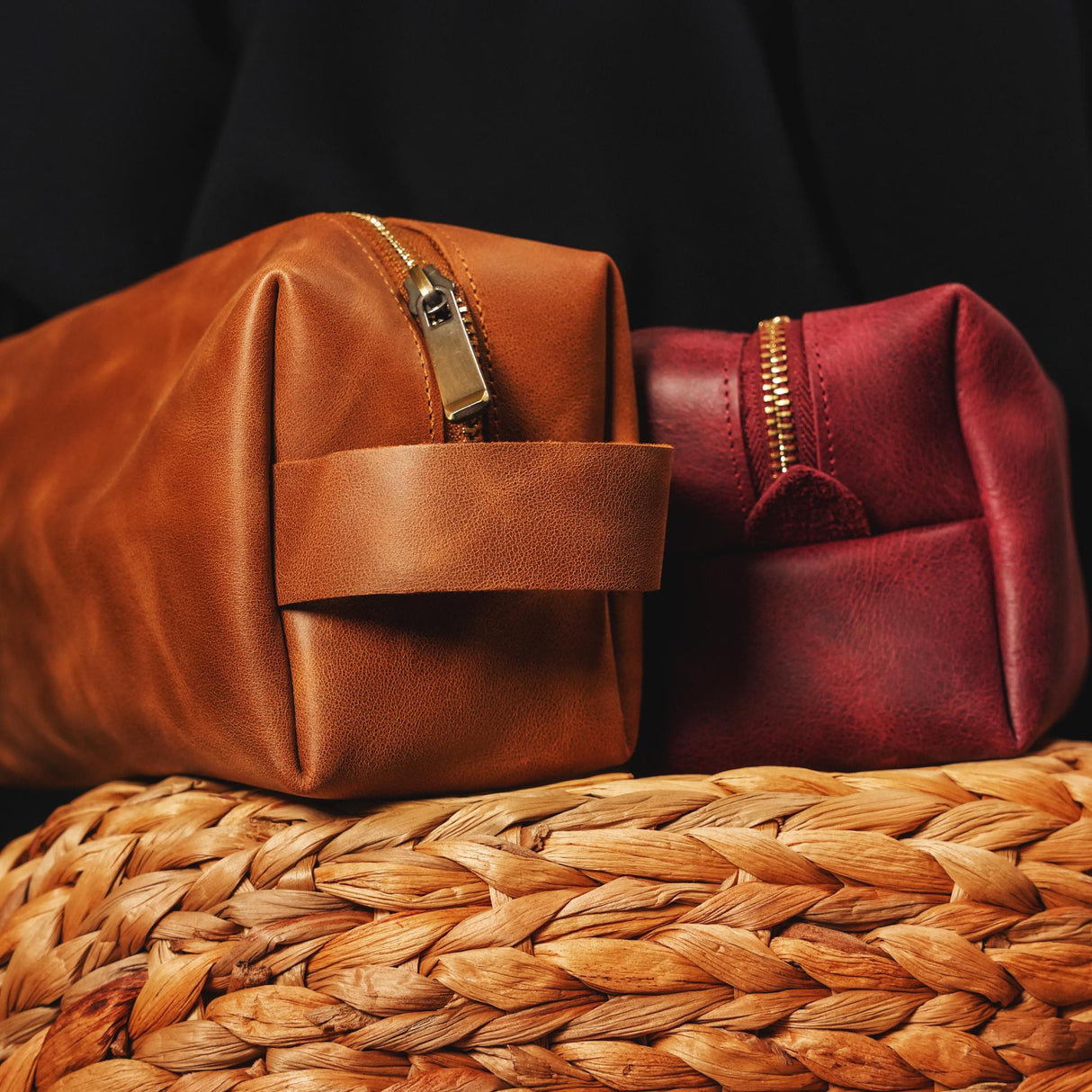 a brown and a red bag sitting on top of a woven basket