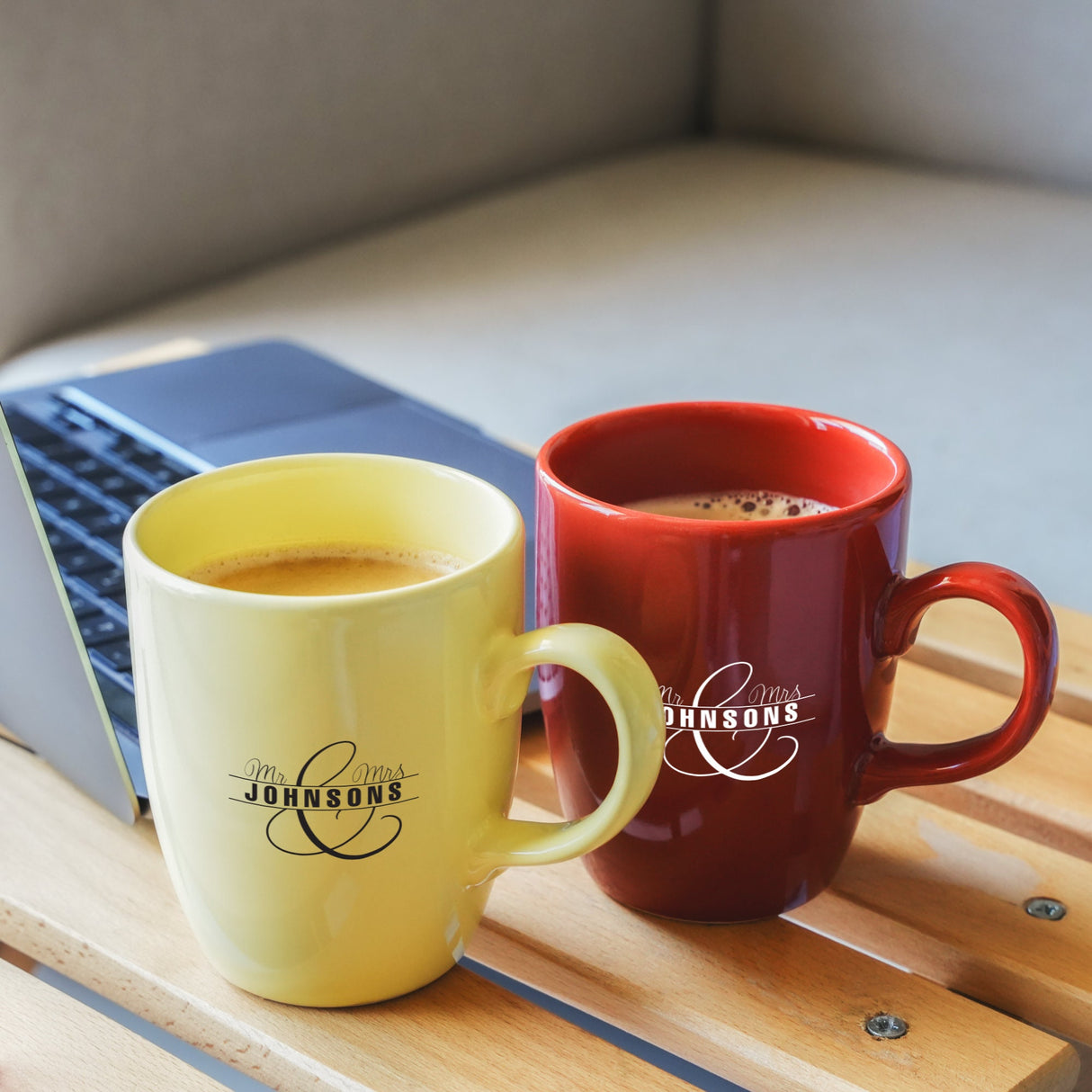 two mugs of coffee sit next to a laptop