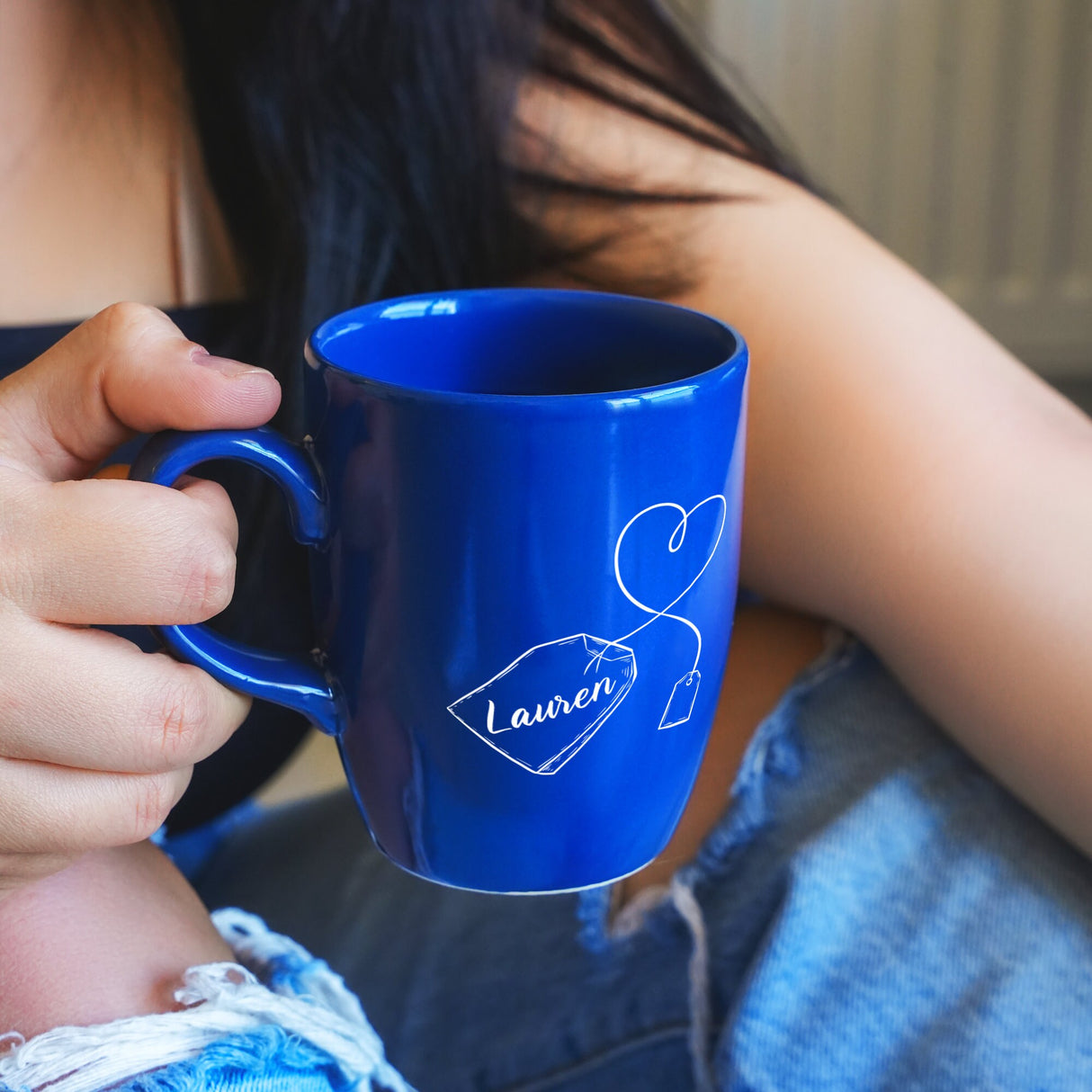 a woman holding a blue coffee mug in her hands