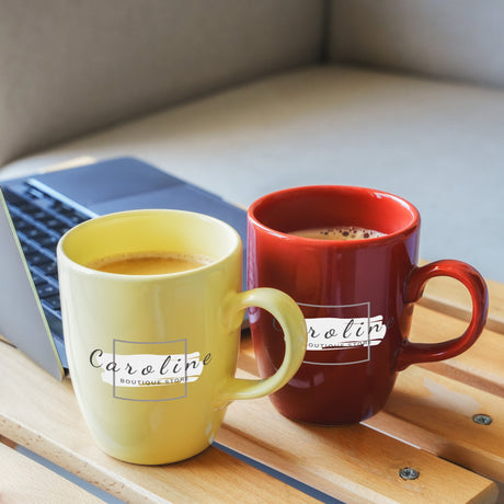 two mugs of coffee sit next to a laptop