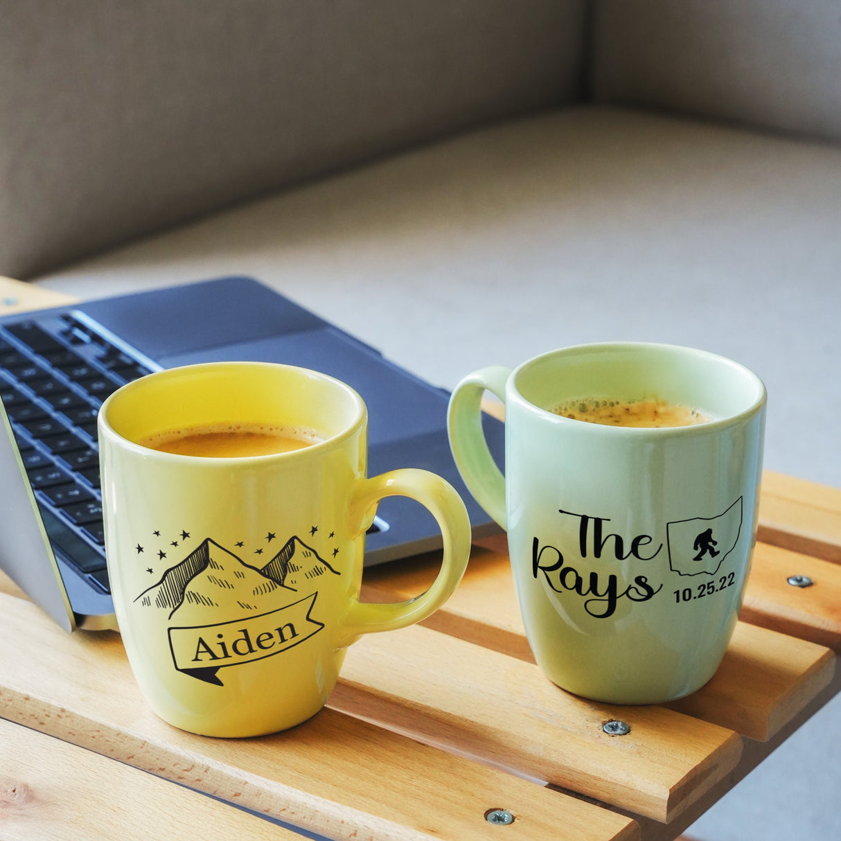 two mugs of coffee sit next to a laptop