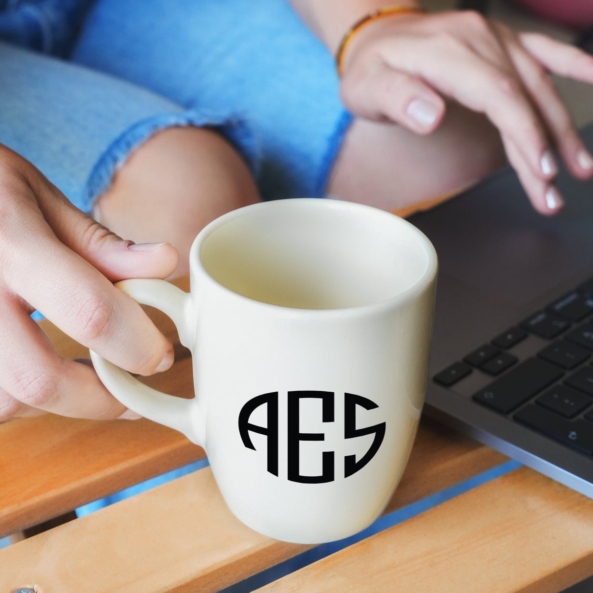 a person typing on a laptop with a coffee mug