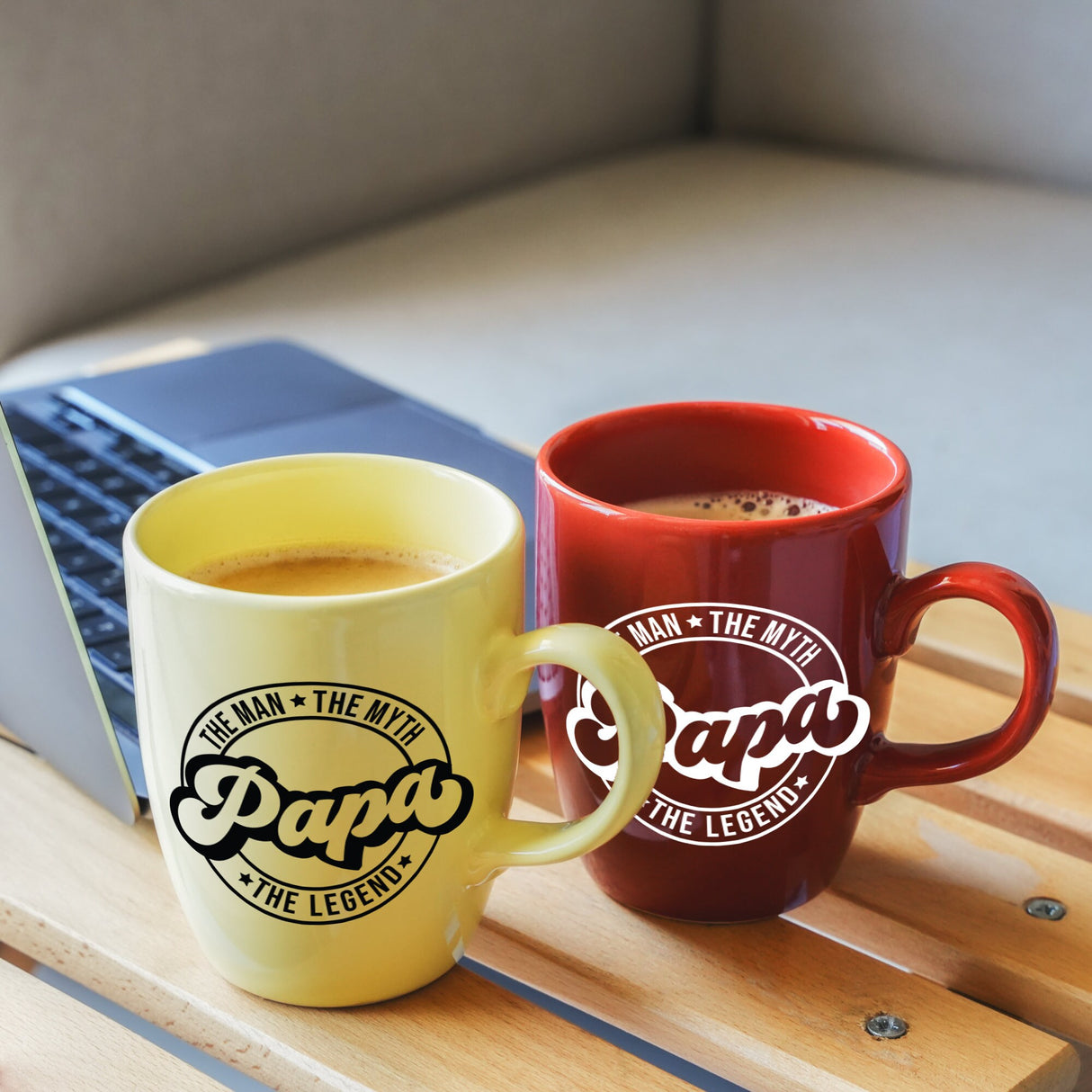 two coffee mugs sitting on a table next to a laptop