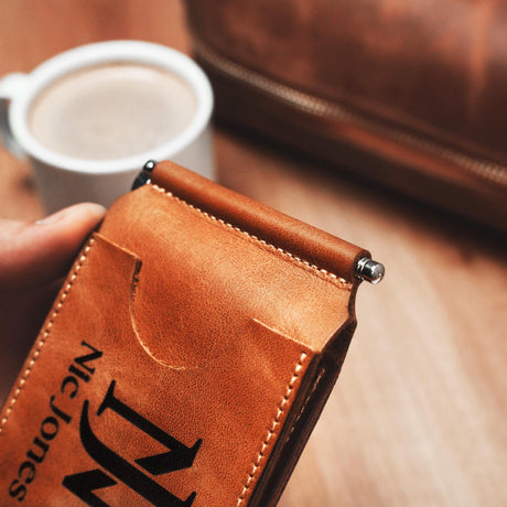 a person holding a leather wallet with a cup of coffee in the background