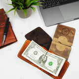 a wallet with a dollar bill sticking out of it next to a laptop