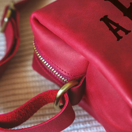 a close up of a red purse on a bed