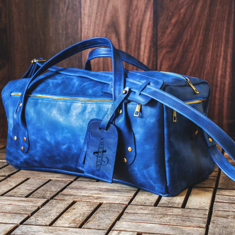 a blue leather duffel bag sitting on a wooden floor