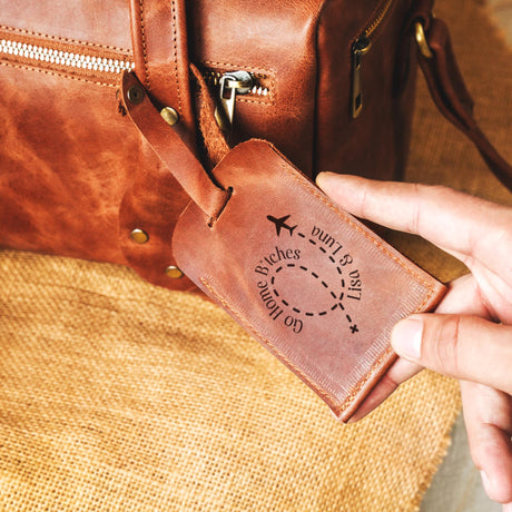 a person holding a brown leather luggage bag