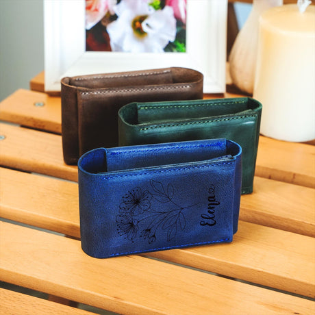 three leather wallets sitting on a wooden table