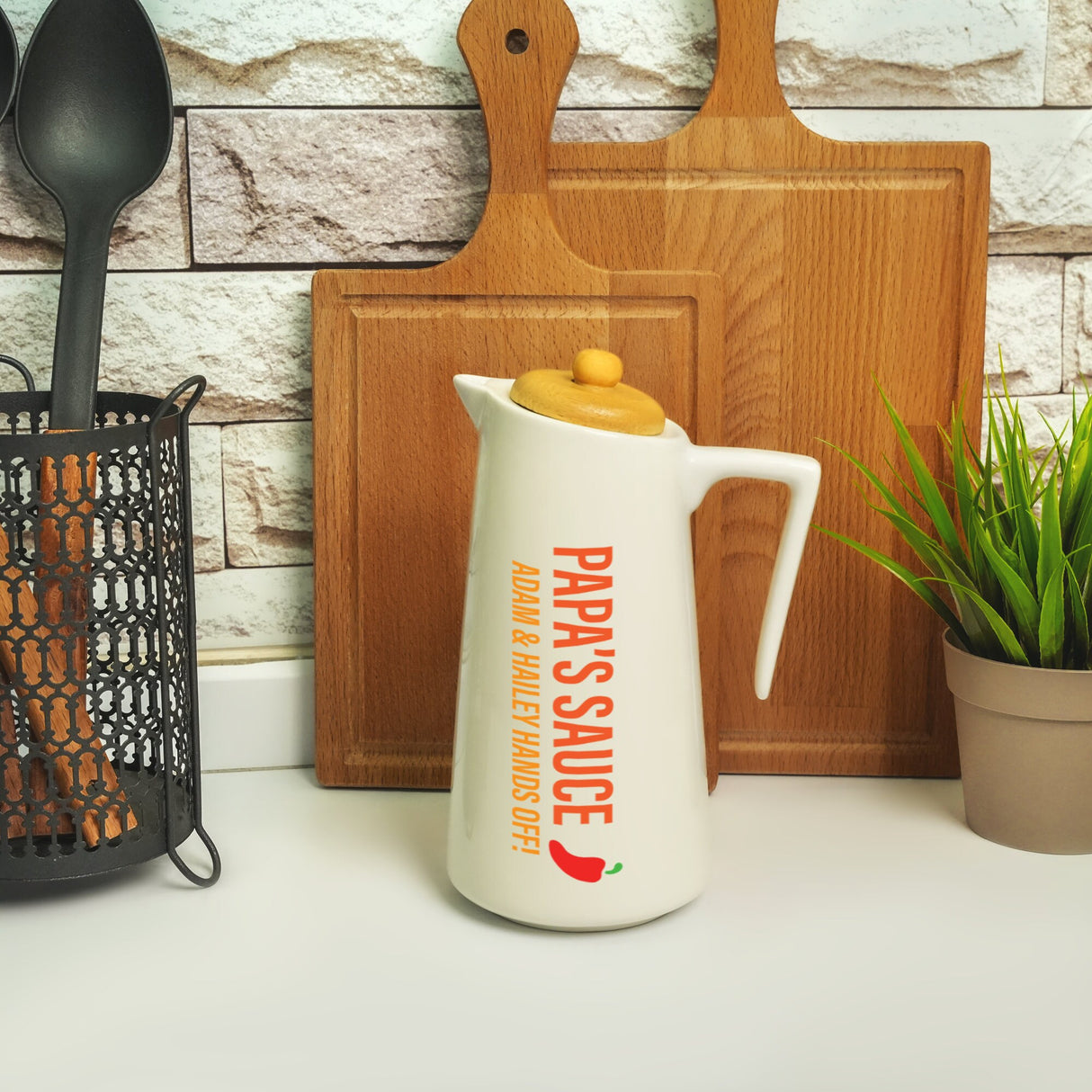 a white pitcher sitting on top of a counter next to a potted plant