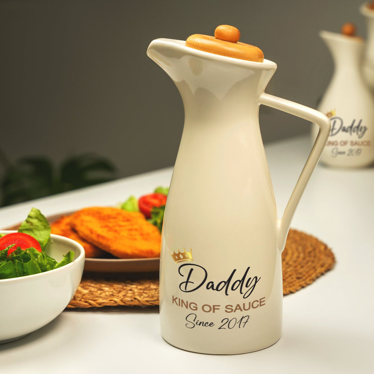 a white pitcher sitting on top of a table next to a bowl of salad