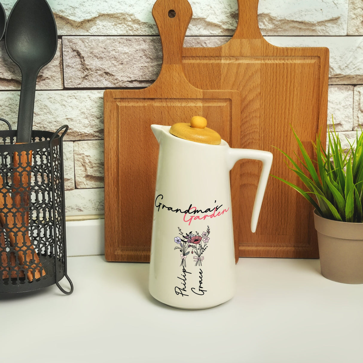 a white pitcher sitting on top of a counter next to a potted plant