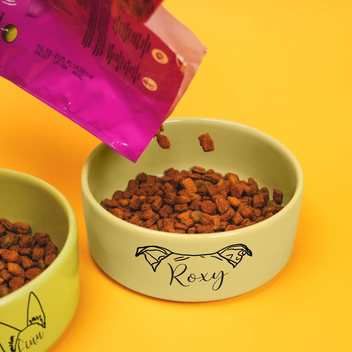 two bowls of dog food on a yellow surface