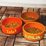 three orange bowls filled with food on top of a wooden table