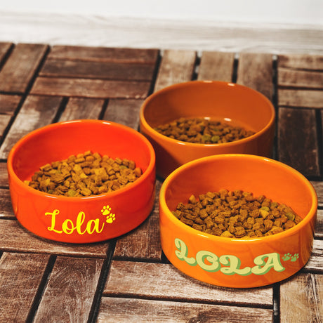 three orange bowls filled with food on top of a wooden table