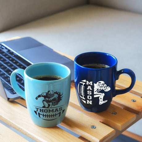 two coffee mugs sitting on a table next to a laptop