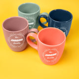 a group of four coffee mugs sitting on top of a yellow table