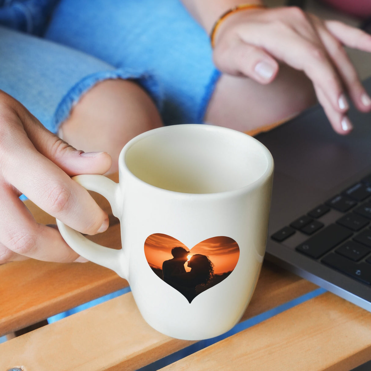 a person holding a coffee mug in front of a laptop