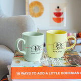 two coffee mugs sitting on top of a stack of books