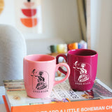 two coffee mugs sitting on top of a book