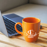 a coffee mug sitting next to a laptop computer