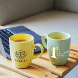 two mugs of coffee sit next to a laptop