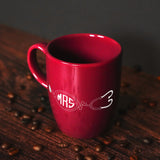 a red coffee mug sitting on top of a wooden table