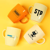 three coffee mugs sitting next to each other on a yellow surface