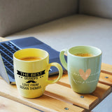 two coffee mugs sitting on a table next to a laptop