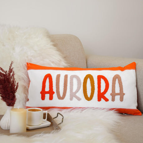 a pillow with the word aurora on it next to a cup of coffee