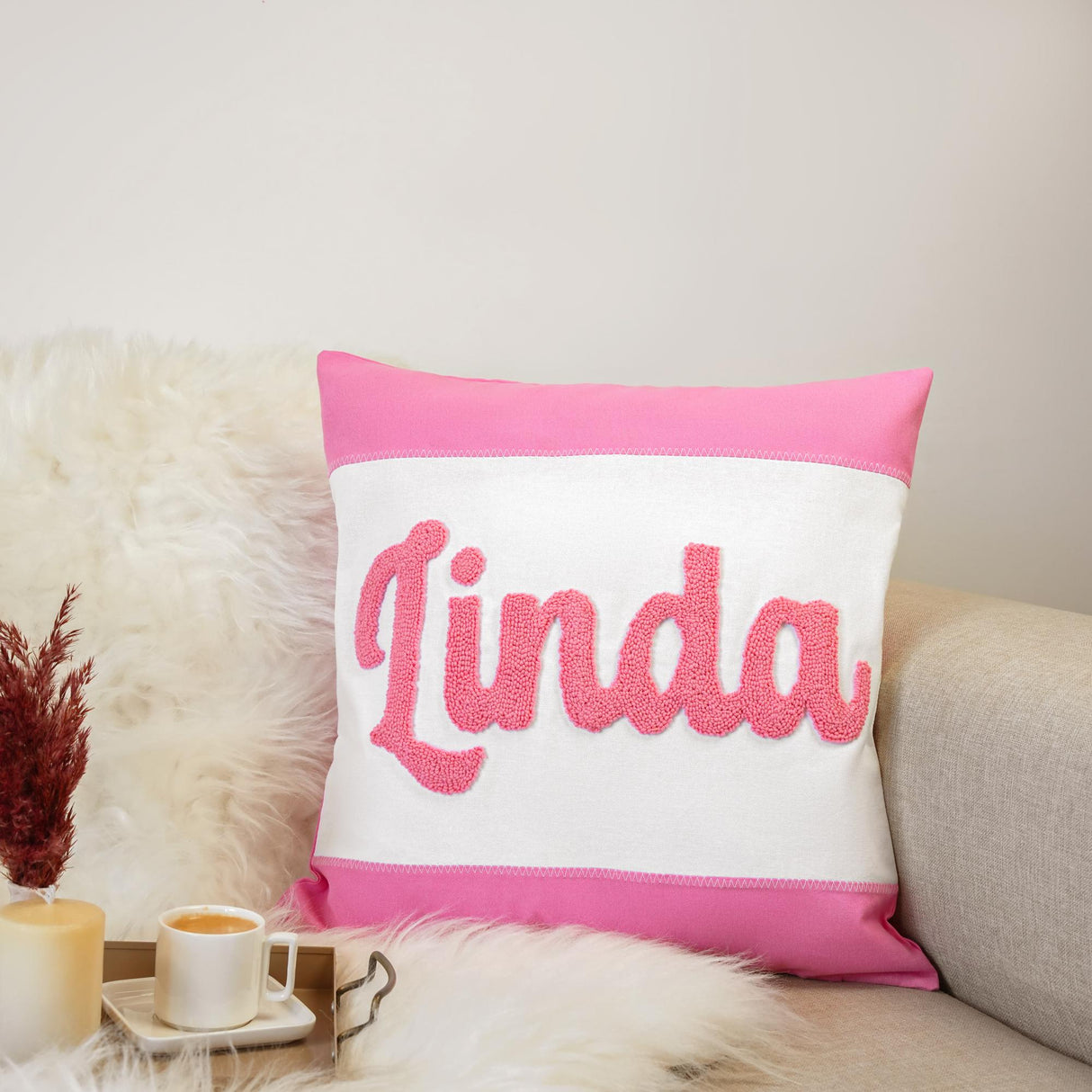 a pink and white pillow sitting on top of a couch