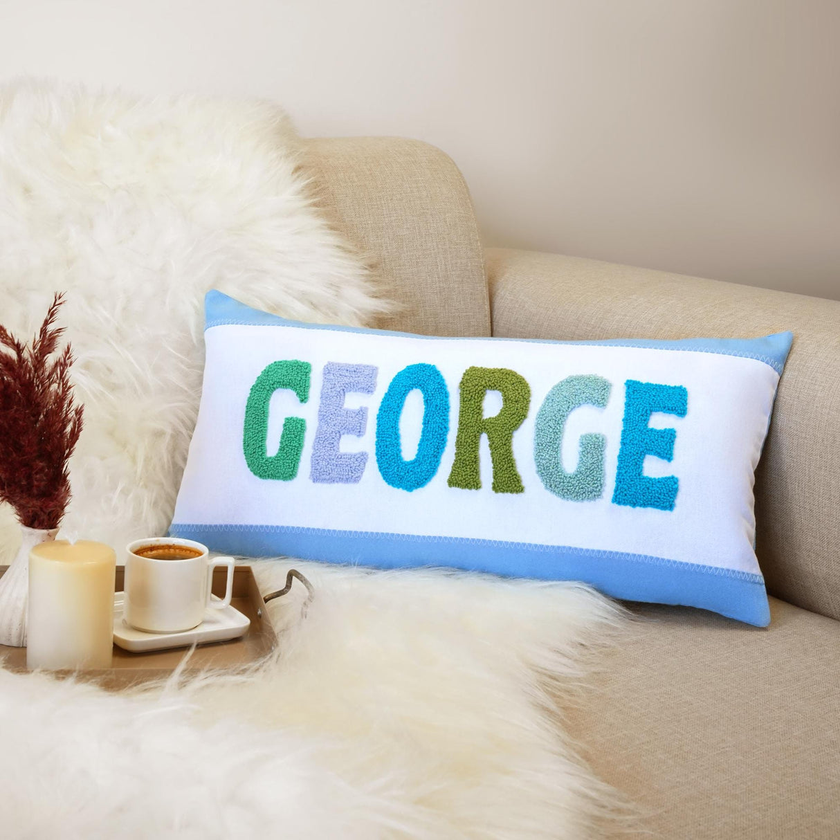 a decorative pillow with the word george on it next to a cup of coffee