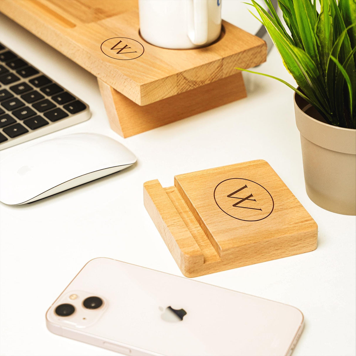 a desk with a keyboard, mouse, cell phone and a plant