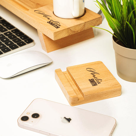 a desk with a laptop, phone and a plant