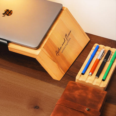 a wooden desk with a laptop and pens