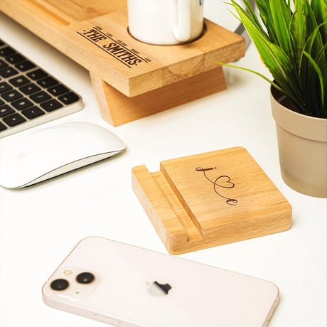 a desk with a cell phone, keyboard, mouse and plant