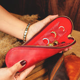 a woman holding a red purse with several rings in it