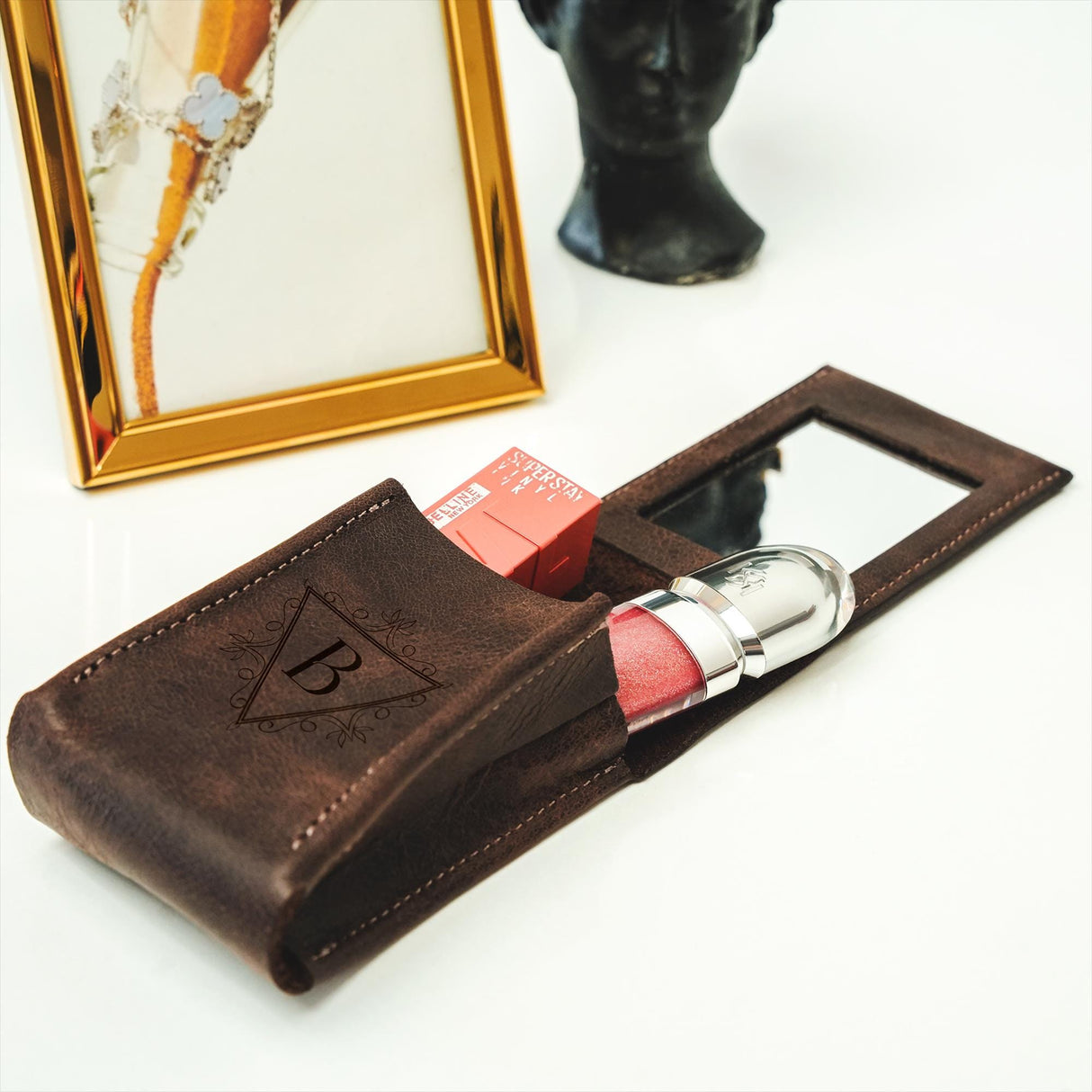 a leather case with lipstick in it next to a mirror