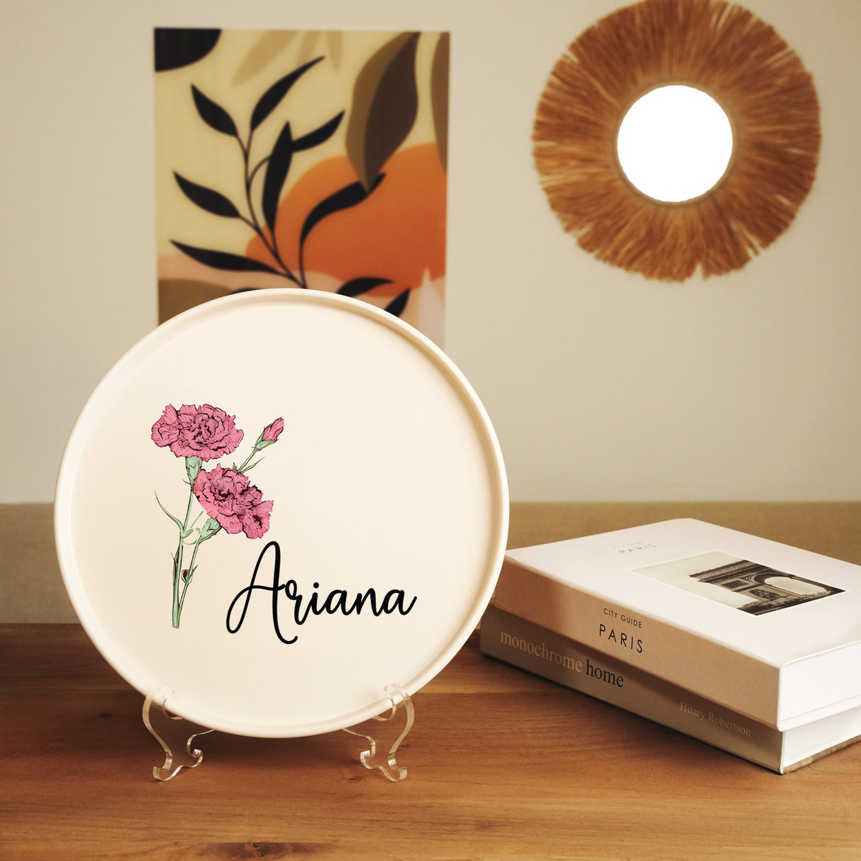 a white plate with a pink flower on it sitting on a table next to a