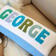 a blue and white pillow with the word george on it