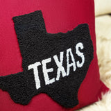 a red pillow with the word texas embroidered on it